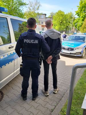 Policjant prowadzący osobę zatrzymaną do radiowozu