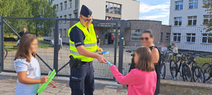 Policjanci przekazujący uczniom materiały profilaktyczne