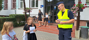 Policjanci przekazujący uczniom materiały profilaktyczne