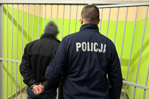 Policjant doprowadzający zatrzymanego mężczyznę