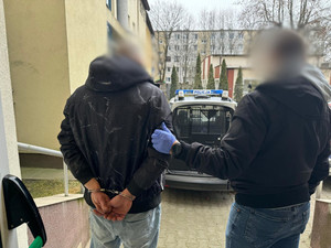 policjant kryminalny doprowadzający zatrzymanego mężczyznę