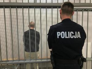 policjant stojący przy zatrzymanym mężczyźnie
